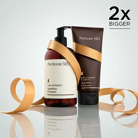 Two Perricone MD cleansers, a pump bottle and a tube, are wrapped with a gold ribbon against a light background, with text in the top right saying 2x BIGGER, and labels reading Perricone MD HIGH POTENCY Nutritive Cleanser on the bottle and Perricone MD HIGH POTENCY CLASSICS Nutritive Cleanser on the tube.