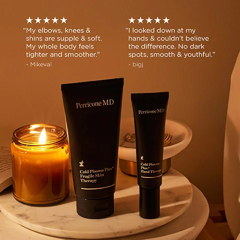 A warm-toned image displays two black Perricone MD product tubes, a larger one labeled Perricone MD Cold Plasma Plus+ Fragile Skin Therapy and a smaller one labeled Perricone MD Cold Plasma Plus+ Hand Therapy, sitting on a marble surface next to a lit candle, with two customer testimonials overhead featuring five-star ratings; the first reads My elbows, knees & shins are supple & soft. My whole body feels tighter and smoother. - Mikeval, and the second reads I looked down at my hands & couldnt believe the difference. No dark spots, smooth & youthful. - bigj.